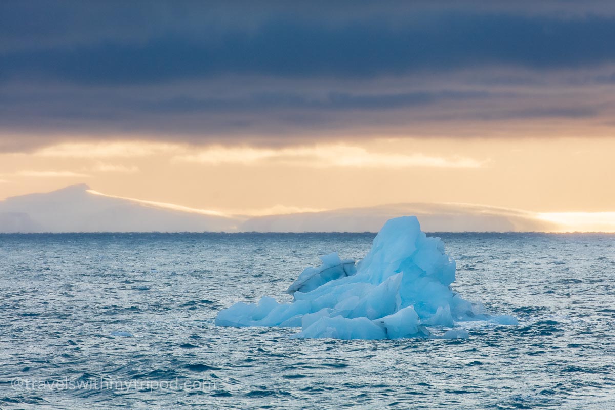 Iceberg floating at sunset